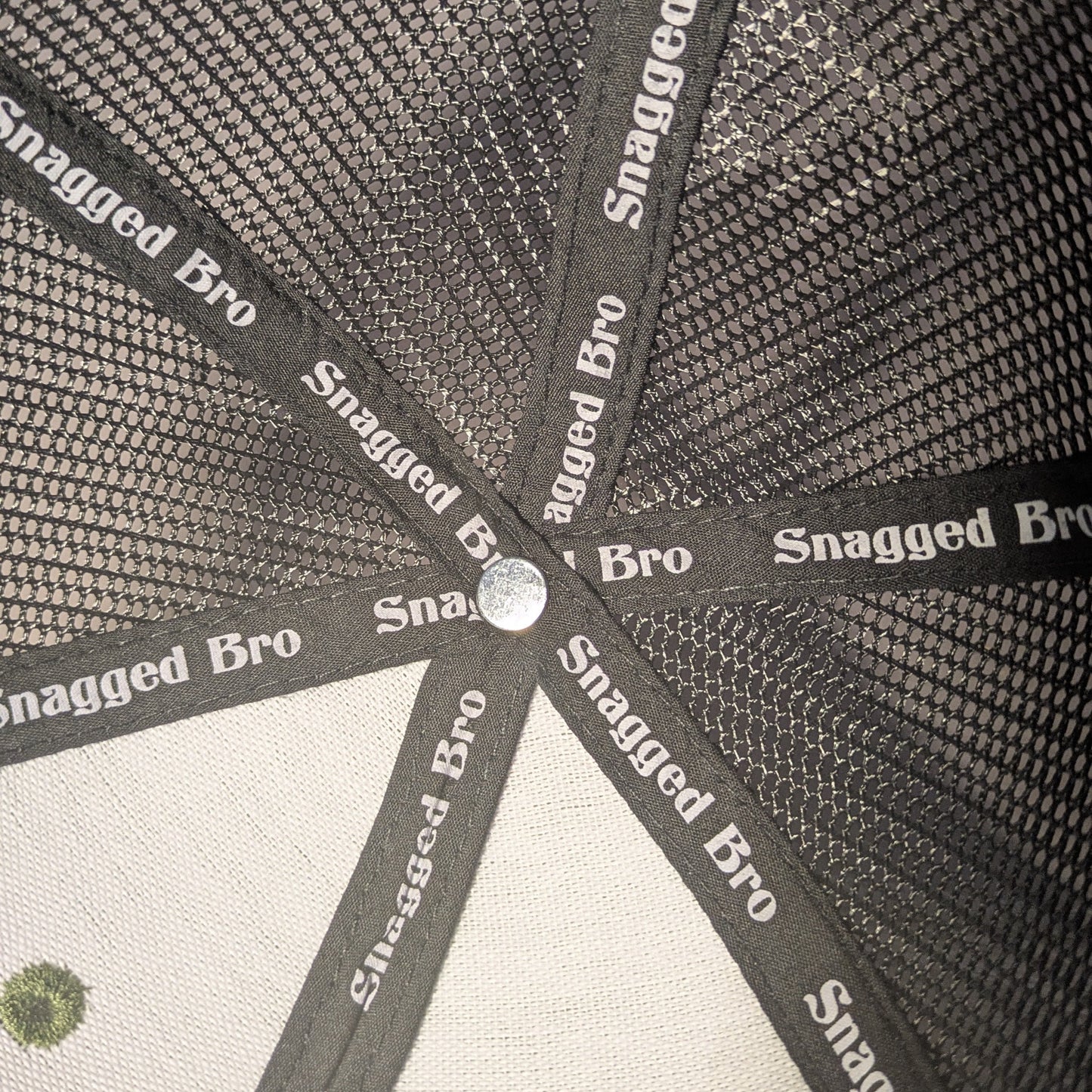 Close-up of a cap with 'Snagged Bro' branding on a textured background