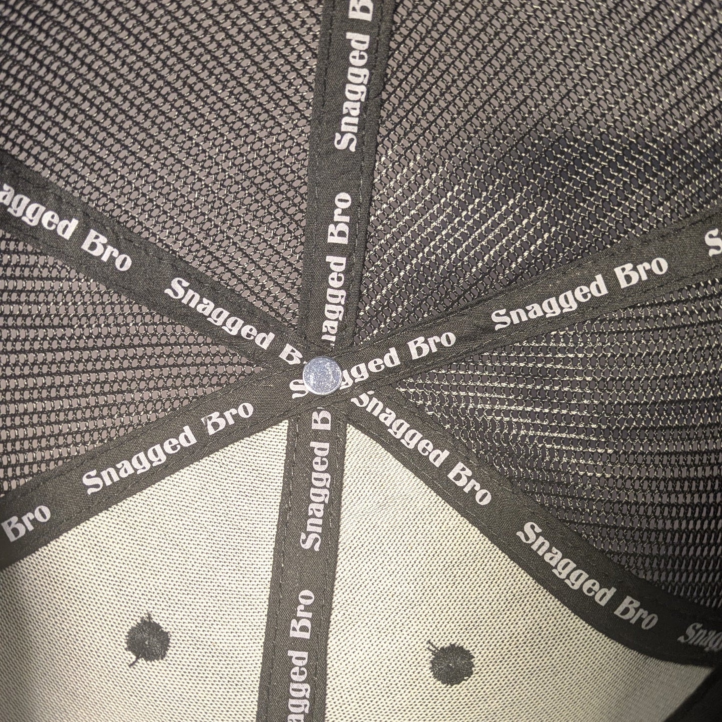 Close-up of a cap with 'Snagged Bro' branding on a black background