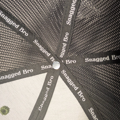 Close-up of a cap with 'Snagged Bro' branding on a textured background