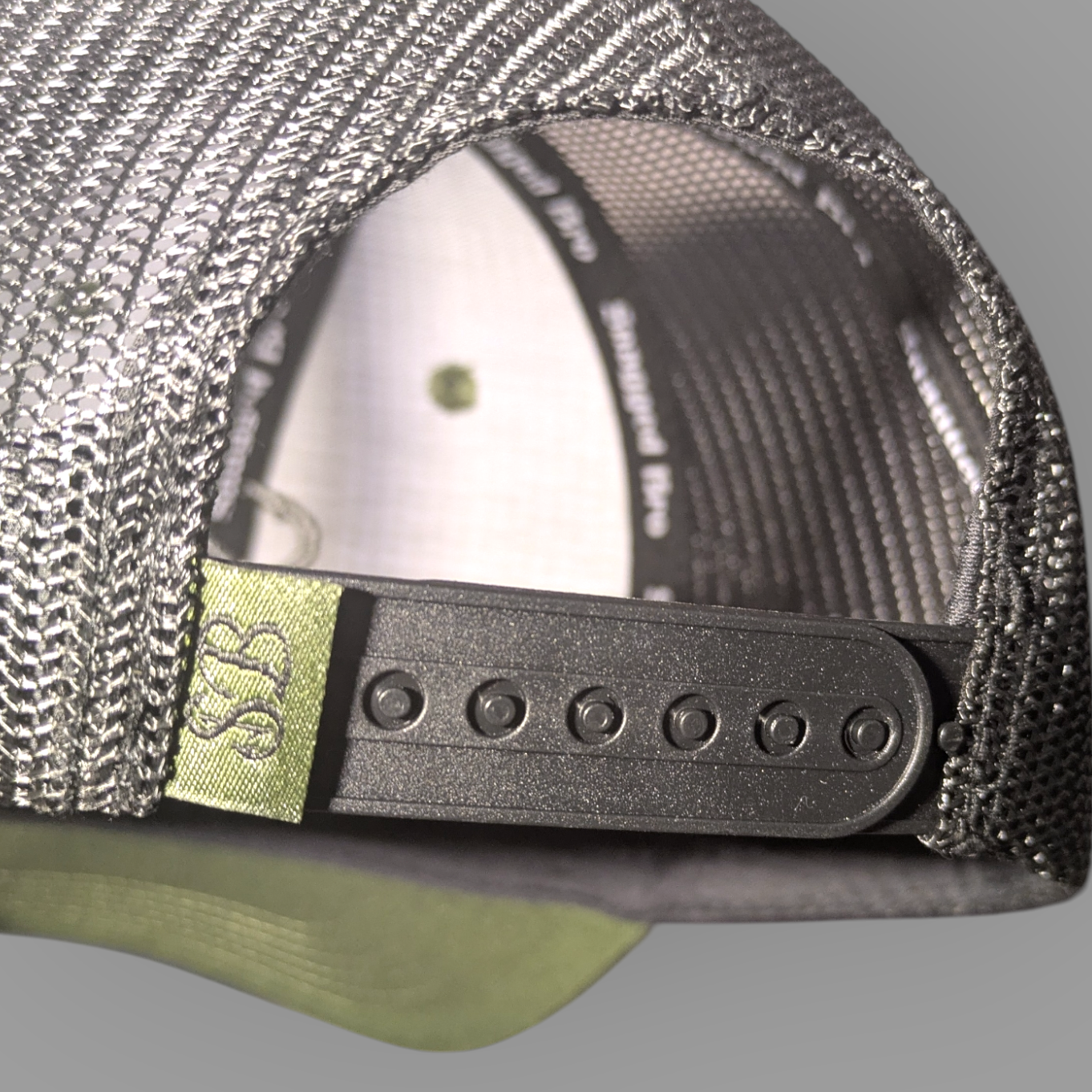 Close-up of a cap's mesh back and logo tag on a gray background