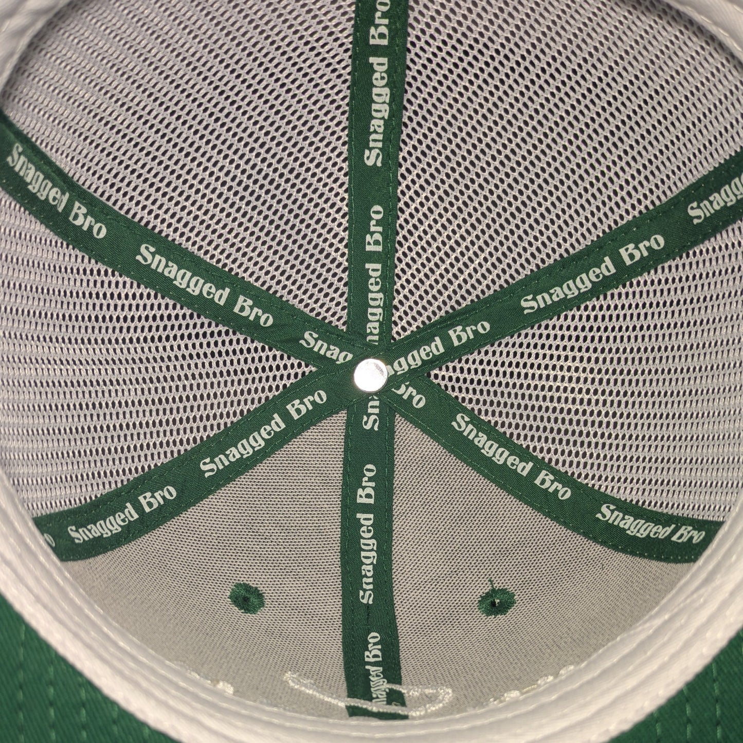 Close-up of a green and gray cap with 'Snagged Bro' branding on the mesh.