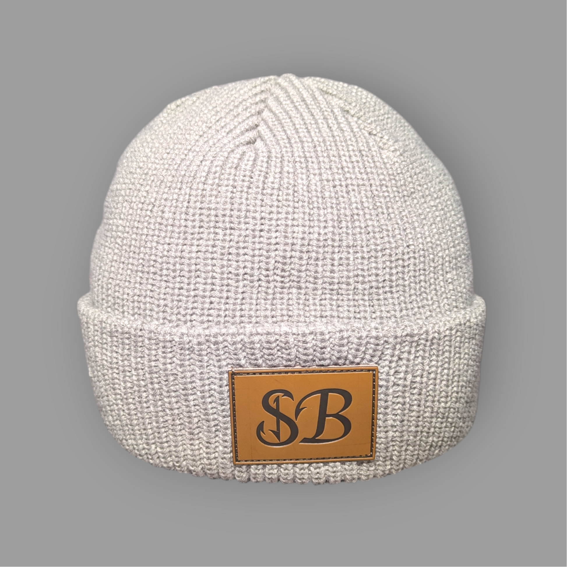 White knit beanie with a brown leather patch featuring 'SB' on a gray background