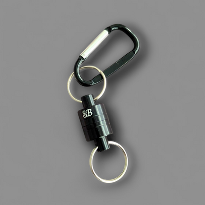 Black carabiner fishing magnet with two keychains on a grey background