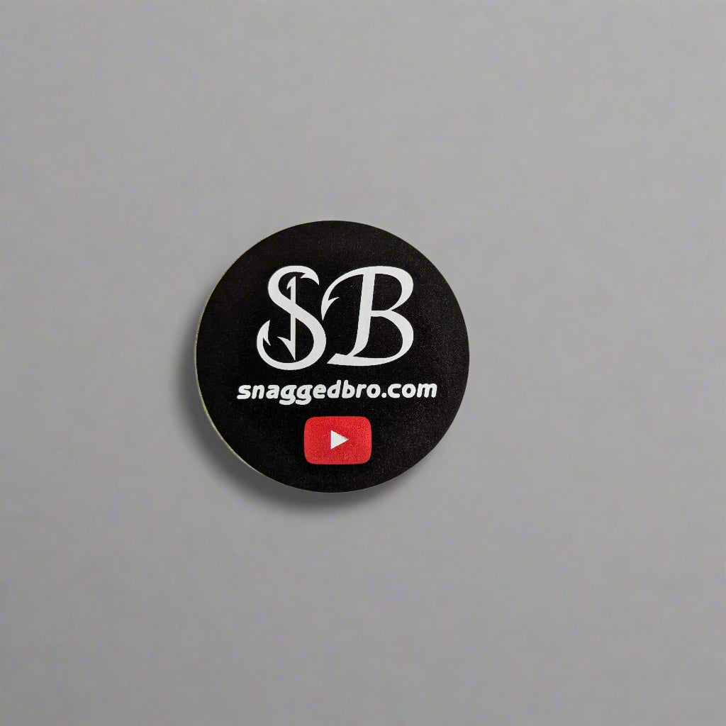 Round black sticker with 'snaggedbro.com' text and YouTube logo on a white background
